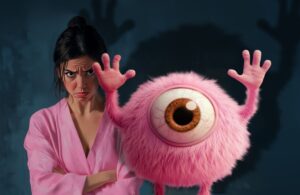 Mammo Monster with raised hands scaring a woman. The woman stands with a sad expression and crossed arms, wearing a pink bathrobe.